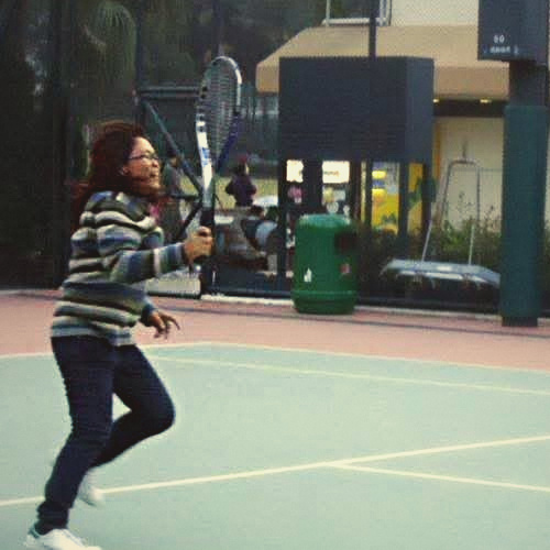 Dhorie mid-swing on a green court