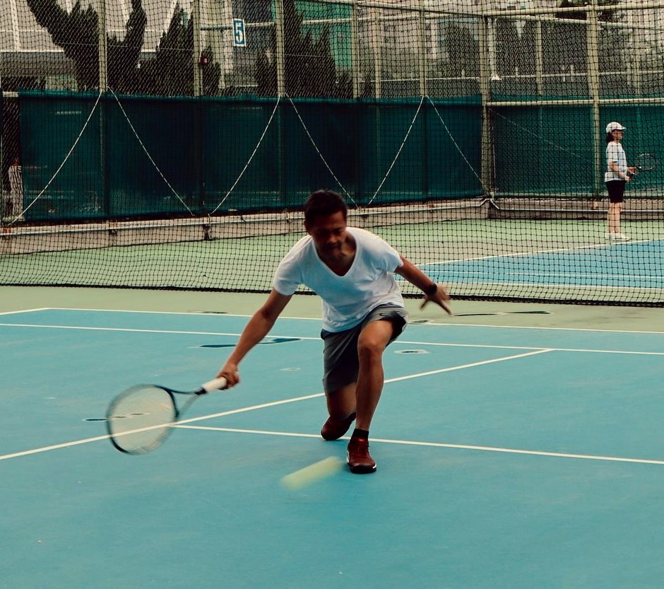 The coach low on a forehand on a blue hard court in Hong Kong
