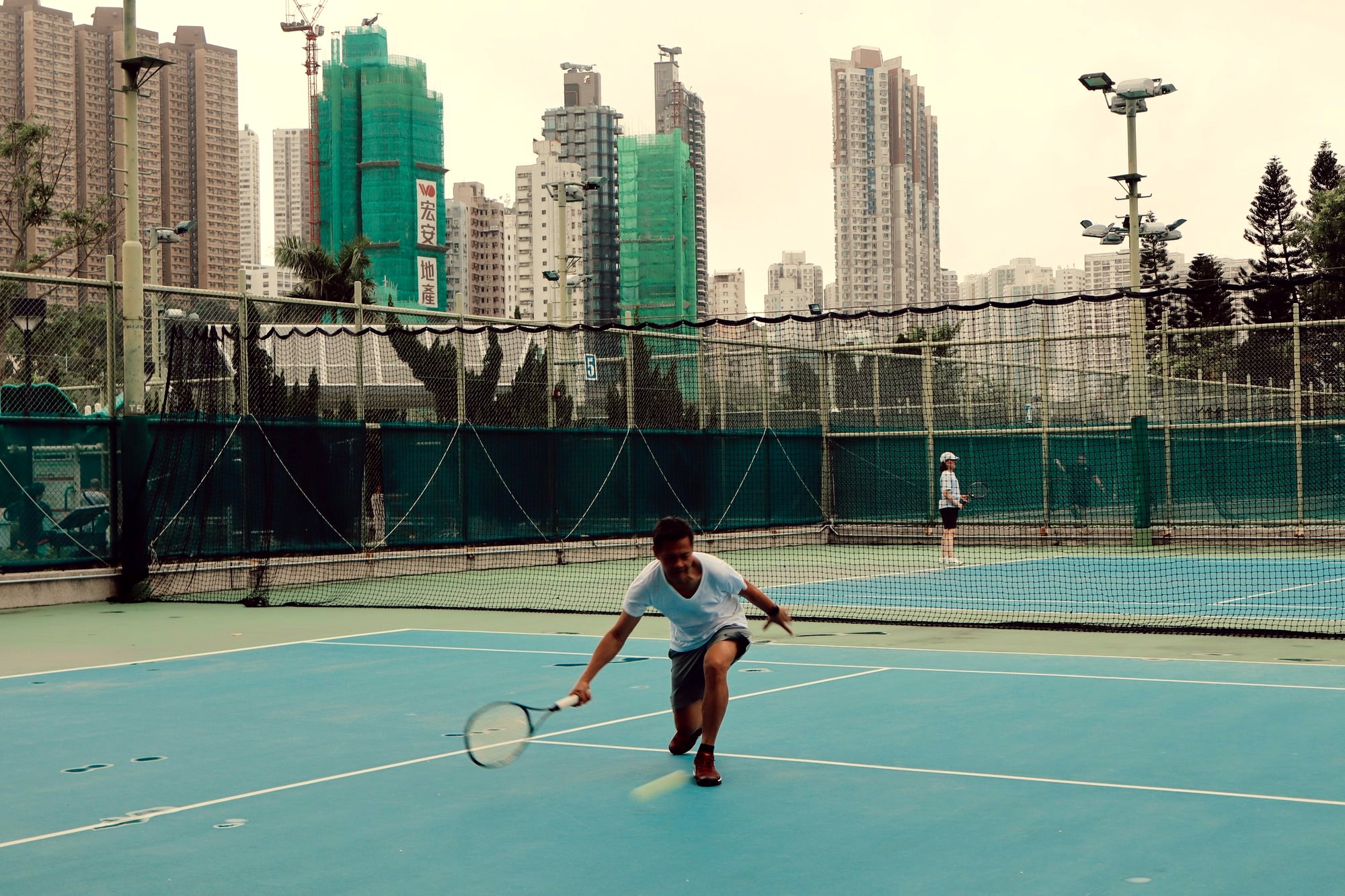 Him on court today, low on a forehand, city towers behind the fence
